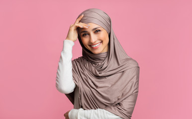 Wall Mural - Shy muslim girl in hijab smiling and touching head in embarrassing