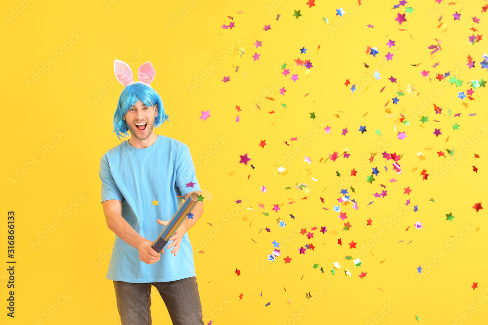 Man in funny disguise and with party noisemaker on color background. April fools' day celebration