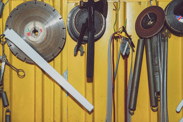 Poster - A set of tools on a yellow wall. Concept of work in a home workshop, doing homework. Tools such as the grinding wheel, saw hang on the wall.
