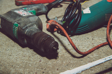 Poster - A set of power tools and tools on concrete ground. The concept of industrial work, renovation, physical work. On the ground lies a screwdriver, grinder, wrench.