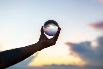 Hand of a young magician guy holding a glass ball for contact juggling at sunset