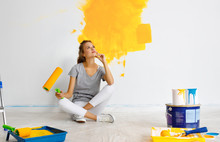 Repair In Apartment. Happy Young Woman Paints Wall .