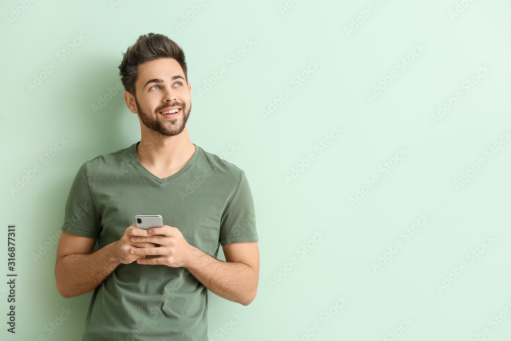 Happy young man with mobile phone on color background - obrazy, fototapety, plakaty 
