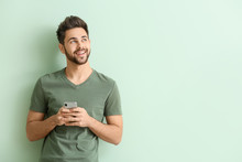 Happy Young Man With Mobile Phone On Color Background
