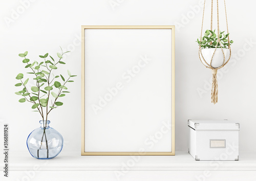 Fotografía Interior poster mockup with vertical gold metal frame on the table with plants in blue vase and hanging macrame pot on empty white wall background