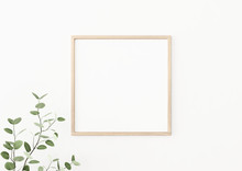 Interior Poster Mockup With Square Wooden Frame On Empty White Wall Decorated With Plant Branch With Green Leaves. 3D Rendering, Illustration.