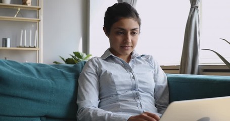 Wall Mural - Young indian woman using laptop sit on sofa at home