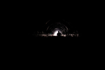 Wall Mural - Silhouette of man walking inside a tunnel