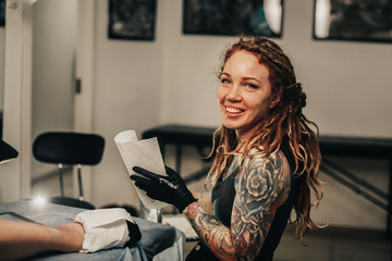 Hipster woman with tattoos dreadlocks makes tattoo