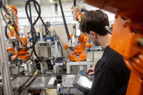 Cuadros en Lienzo Young man programming industrial automatic robot in automotive industry