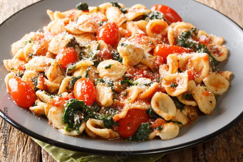 Fotografía Tasty pasta orecchiette cooked with spinach and parmesan cheese in tomato sauce close-up in a plate