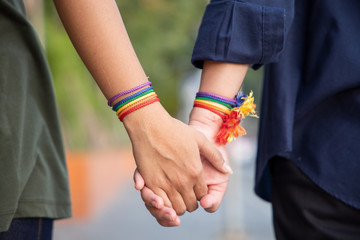 hand of LGBT women holding together with rainbow ribbon symbol; concept of LGBT pride, LGBTQ people, lgbt rights campaign, same sex marriage