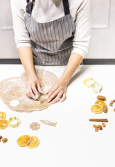 Wall Mural - Young pretty woman prepares the dough and bakes gingerbread and cookies in the kitchen. She makes a star shape on the dough. Merry Christmas and Happy New Year.