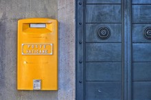 Yellow Post Box On The Wall Next To A Blue Metal Door