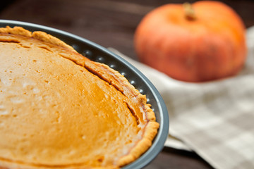 Pumpkin pie on white ceramic plate on brown wooden table. Female hand with knife. Woman cuts a Thanksgiving pie