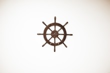 High Angle Shot Of A Small Wooden Ship's Helm On A White Surface