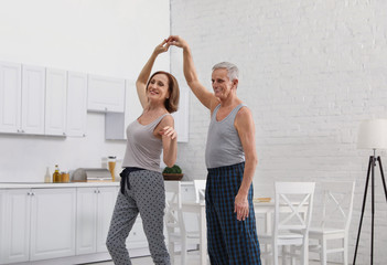 Wall Mural - Happy senior couple dancing together in kitchen