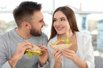 Wall Mural - Happy couple having breakfast with sandwiches at home