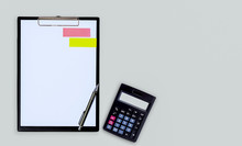 Black Clipboard, Pen And Calculator On Grey Color Background.