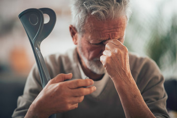 Old man with crutches. Senior man having pain.