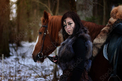 Cuadros en Lienzo a Viking girl next to a red horse painted in black runes.