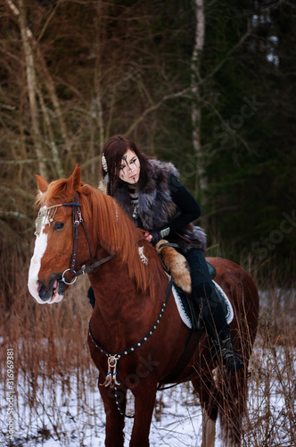 Fotografía a Viking girl riding a red horse painted in black runes
