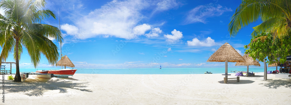 Panorama beautiful beach with white sand, turquoise ocean and blue sky with clouds on Sunny day. Summer tropical landscape with green palm trees and Straw umbrellas with empty copy space. - obrazy, fototapety, plakaty 