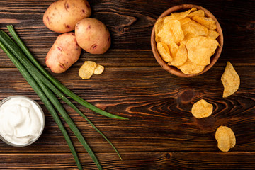 Wall Mural - Crisps and green onion on dark wooden background.