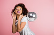 © LIGHTFIELD STUDIOS - smiling african american girl in paillettes dress holding disco ball, isolated on pink with confetti