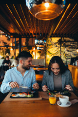 Poster - happy young couple having lunch in restaurant