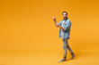 © ViDi Studio - Excited young bearded man in casual blue shirt posing isolated on yellow orange background studio portrait. People sincere emotions lifestyle concept. Mock up copy space. Pointing index fingers aside.