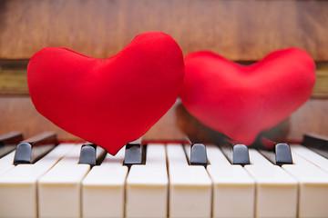 Two red hearts lie on the piano keyboard. The concept of music for love.