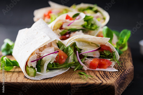 Fotografía Fresh tortilla wraps with chicken and fresh vegetables on wooden board