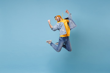 Wall Mural - Cheerful young hipster guy in fashion jeans denim clothes posing isolated on pastel blue background studio portrait. People emotion lifestyle concept. Mock up copy space. Jumping doing winner gesture.