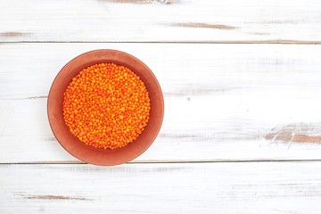 lentil grains in a cup on a light wooden background.