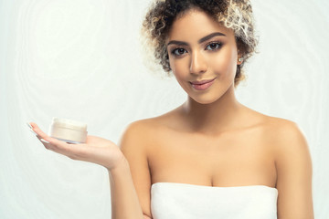 Close-up portrait of happy young beautiful woman holding moisturizing facial cream - isolated on white