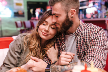 Canvas Print - Loving couple in retro bright street food cafe hugging.