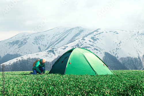 Tourist pitch a tent on green meadow in spring mountains. Amazing highland. Landscape photography