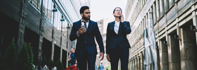 Content business partner walking in downtown street with smartphone