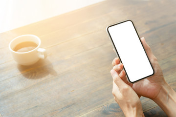 Mockup image blank white screen cell phone.man hand holding texting using mobile on desk at coffee shop.background empty space for advertise text.people contact marketing business,technology 