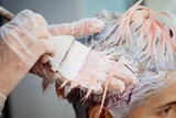Hairdresser colorist dyes the hair of a woman to a client in different colors.