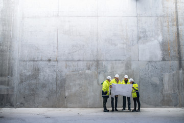 a group of engineers standing against concrete wall on construction site.