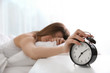 © New Africa - Young woman turning off alarm clock at home in morning, focus on hand