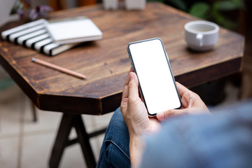 Mockup image blank white screen cell phone.woman hand holding texting using mobile on desk at coffee shop.background empty space for advertise text.people contact marketing business,technology 