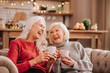 © zinkevych - Two grey-haired pleasant cute ladies sitting on the sofa and looking amazing