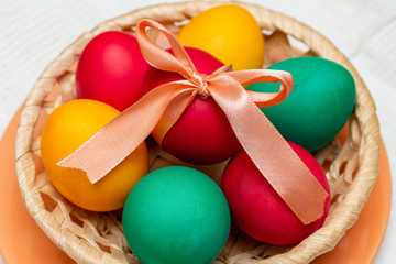  Colorful painted eggs with bow for Easter in a basket