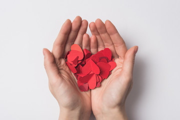 Wall Mural - partial view of woman holding paper red hearts on white background