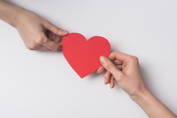 Wall Mural - cropped view of women holding red heart on white background