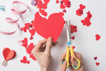 Wall Mural - cropped view of woman holding red heart and scissors on white background