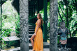 Beautiful woman in orange dress standing on footbridge in Bali